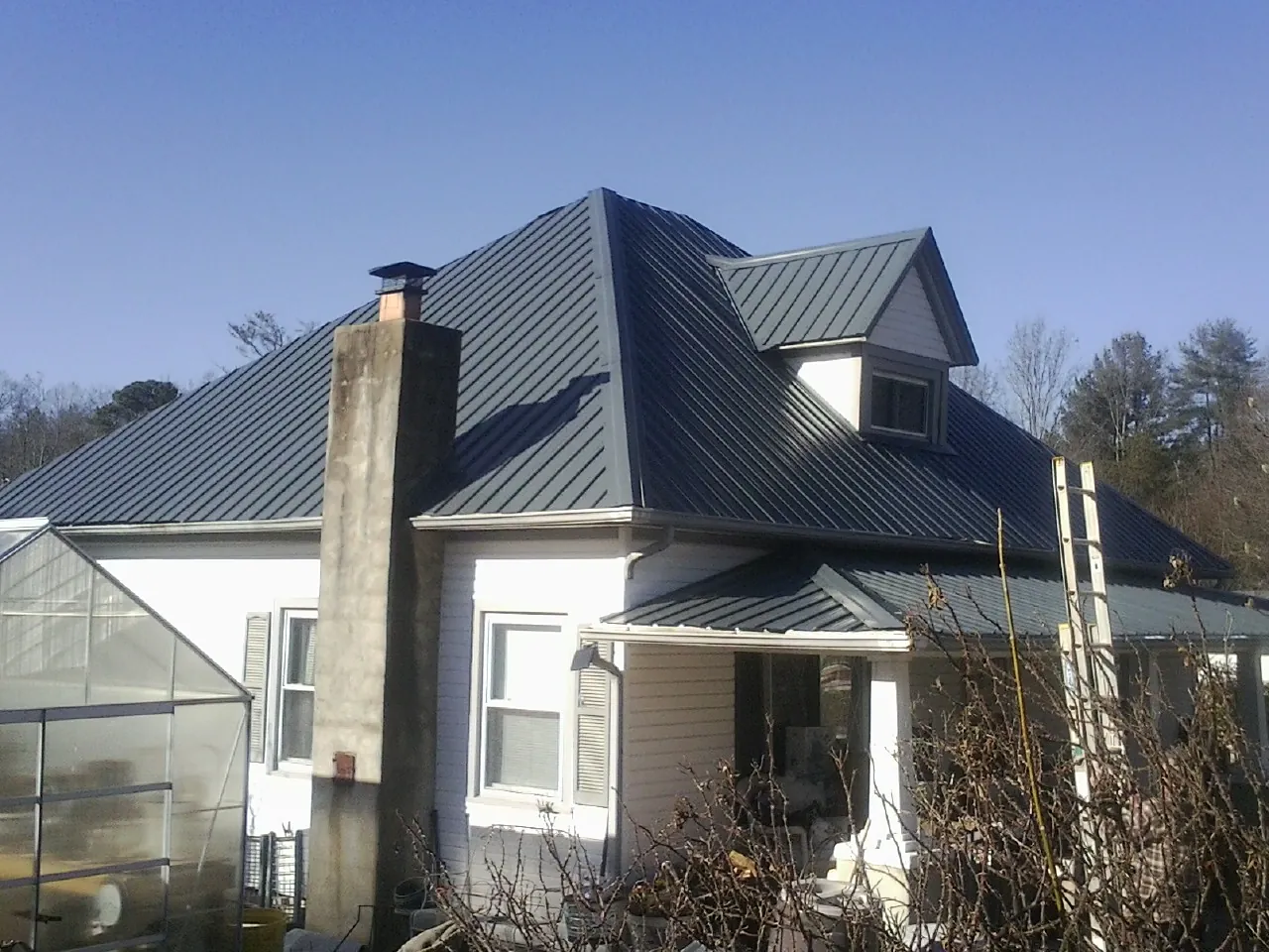 Dark blue standing seam metal roof on a white farmhouse with dormer — Slate & Tile Roof Repair by Roofing Brothers in Howard Lake