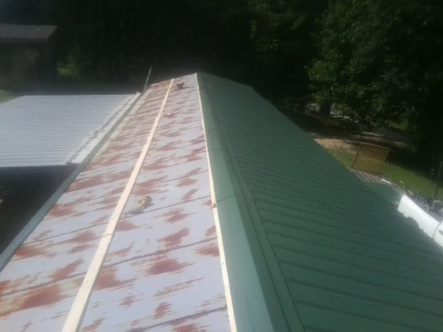 Old rusted panels beside newly installed green metal roofing — Wind Damage Roof Repair by Roofing Brothers in Howard Lake