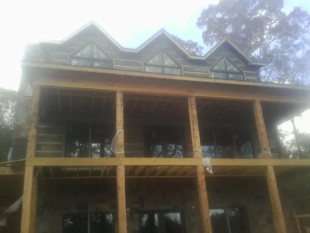 Dormers and porch framing on a large log home under construction — Roof Coating work by our crew in Howard Lake