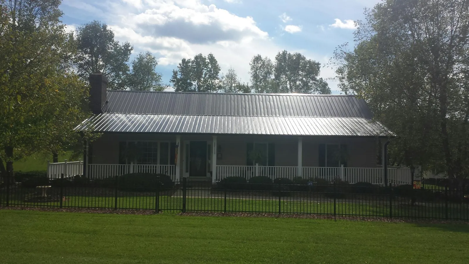 Gray metal roof on a brick ranch with a full width front porch — Gutter Guard Installation work by our crew in Howard Lake