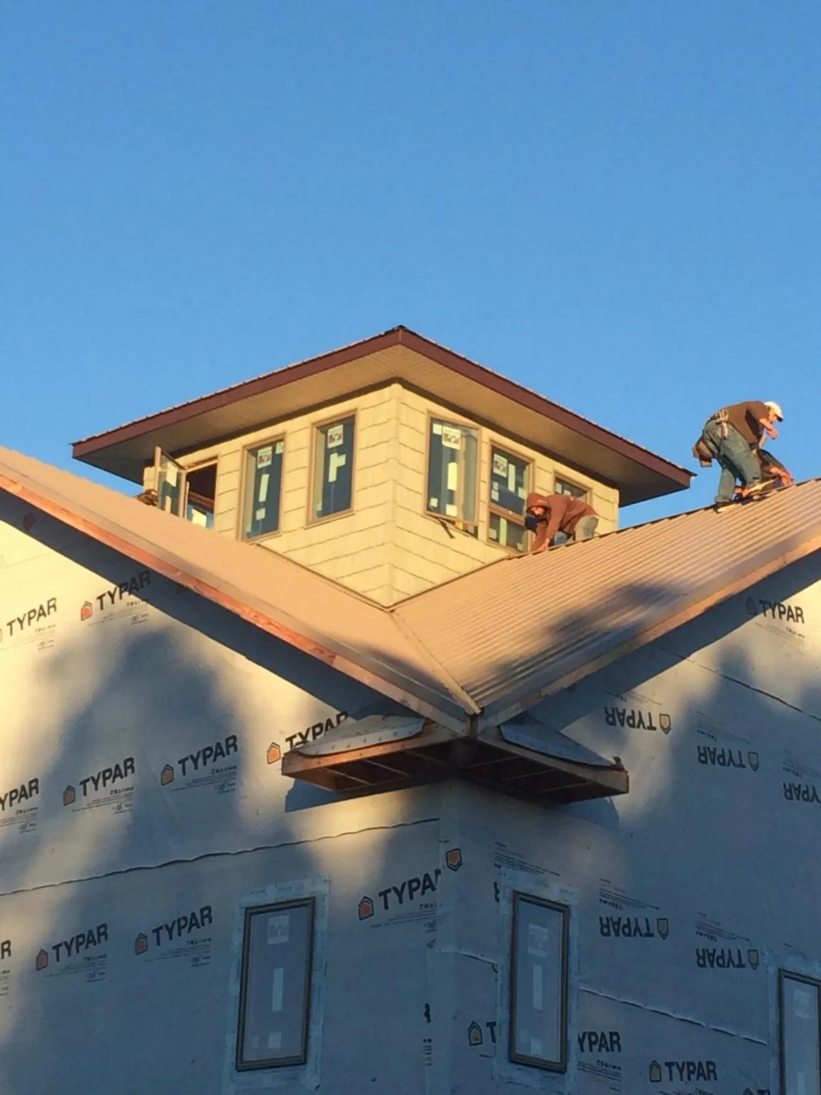 Roofers working around a rooftop cupola on a new metal roof at sunset — Roof Waterproofing in Howard Lake by Roofing Brothers